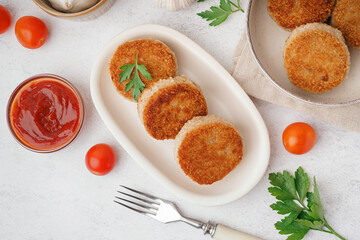 Plate and bowl of tasty meat cutlets with sauce on white background