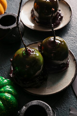 Plates of tasty caramel apples for Halloween on black background