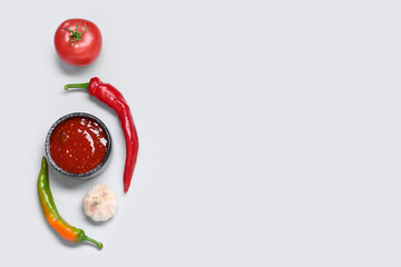 Bowl with tasty salsa sauce and ingredients on grey background