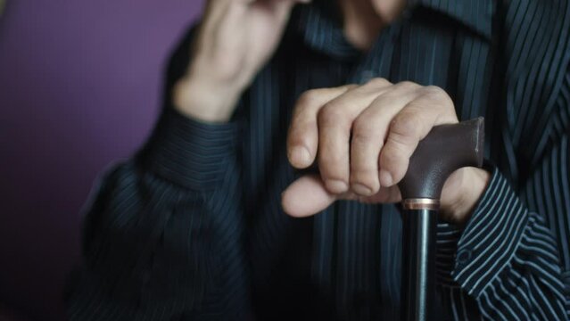 Closeup, senior and hands of man with cane for support, walking help and aging. Morning, house and elderly person with gear for a walk on the living room sofa for healthcare and holding for strength.