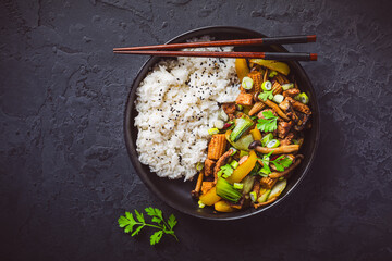Stir-fry with mushrooms, vegetables and rice on dark background