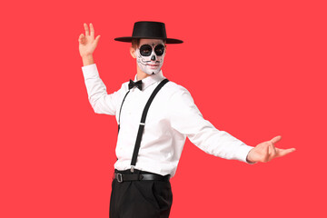 Young man with painted skull on red background. Mexico's Day of the Dead (El Dia de Muertos) celebration