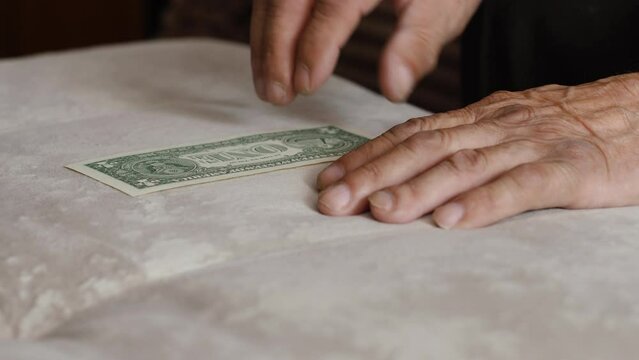 An old man examines a dollar bill. Bankruptcy and elder fraud.
