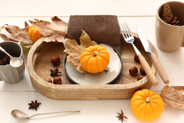 Autumn table setting with pumpkins, chestnuts and dried leaves on white wooden background