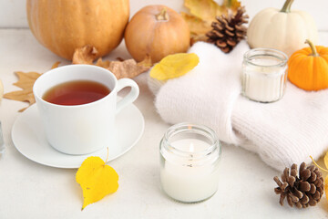 Cup of tea, autumn leaves, sweater and burning candles on white background