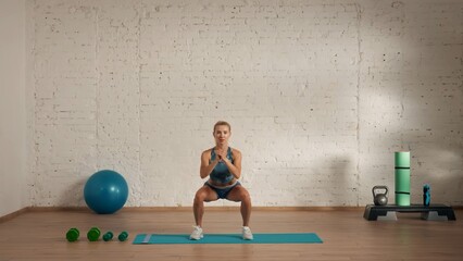 Healthcare creative advertisement concept. Woman fitness coach in the room doing squats for...