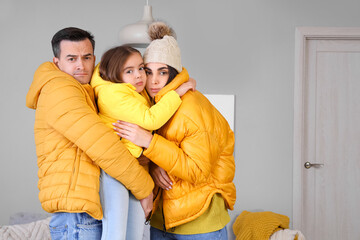 Frozen family in puffer jackets with lack of heating at home