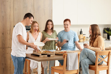 Group of young friends eating pizza at home party