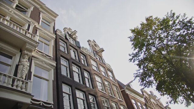 Low angle view of beautiful canal-side houses with lifting beams located on the Wallen in Amsterdam, the Netherlands