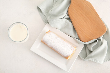 Plate with sweet sponge cake roll and glass of milk on white background