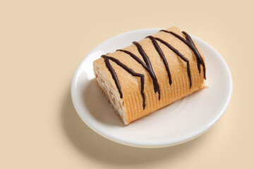 Plate with sweet sponge cake roll on yellow background