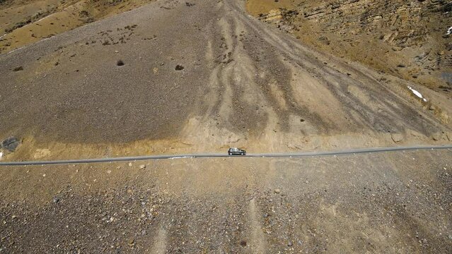 Aerial drone following shot of a car passing sand mountain in Spiti valley, Himachal Pradesh, India. Himalaya adventure travel expedition.
