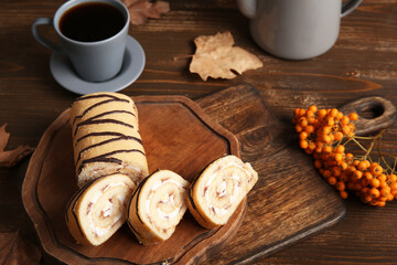 Boards with sweet cut sponge cake roll and rowan on wooden background
