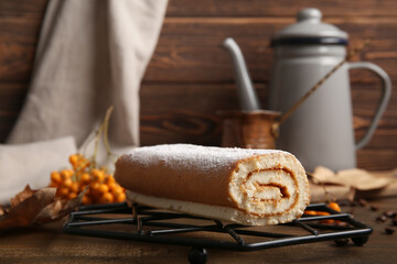 Grid with sweet sponge cake roll on wooden background