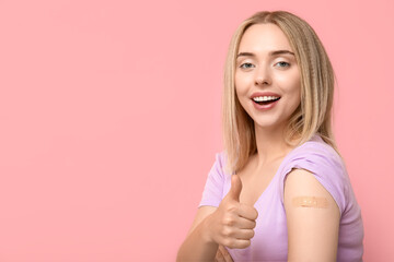 Young woman with medical patch on arm showing thumb-up against pink background. Vaccination concept