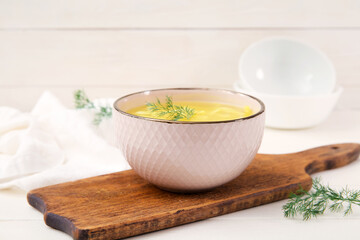 Bowl of tasty chicken soup on white wooden background