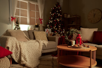 Interior of living room with sofas and Christmas cookies on table at night