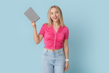 Beautiful young happy woman with book on blue background