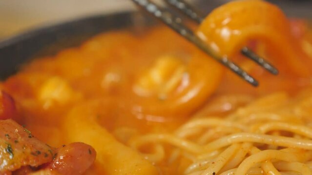 The flower-shaped denominator of Snow Rose Tteokbokki covered in white cheese powder, long wheat rice cake and pasta