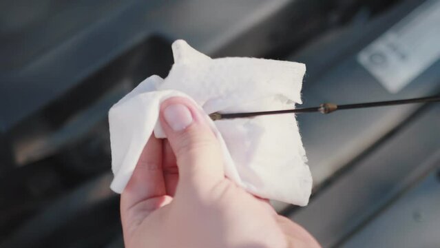 Check the oil level on the oil dipstick, wipe the dipstick with a napkin. Engine lubrication system, close-up. Slow motion