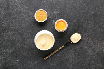 Bowls of fresh mayonnaise and ingredients on black background