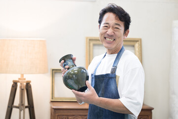 壺を持って鑑定する男性　カメラ目線 © kapinon