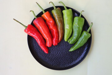 green to red colors chilli peppers on white plate