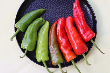 green to red colors chilli peppers on white plate