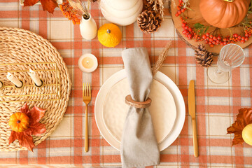 Autumn table setting with folded napkin, golden cutlery and pumpkins, closeup