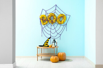 Word BOO made of balloons with web on blue wall in room