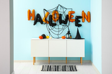 Word HALLOWEEN made of balloons with web on blue wall in living room interior