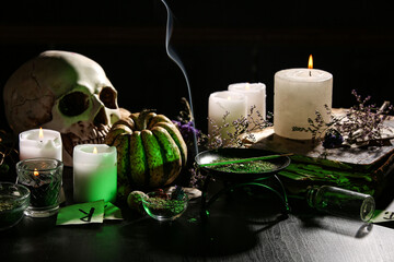 Witch's magic attributes with burning candles on dark table, closeup