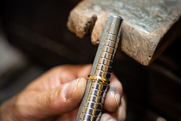 Jeweler hands measuring and checking ring size gauge mandrel. Goldsmith working repairing a gold jewel in his jewelry workshop.
