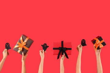 Women with Halloween gifts and paper ghosts on red background