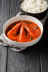 Whole Tiger Prawn Malai Curry served with white rice closeup on the wooden table. Vertical