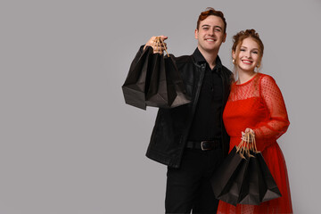 Young couple with shopping bags on grey background. Black Friday sale
