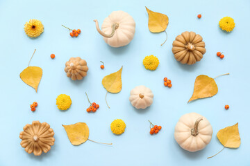 Beautiful composition with candles in shape of pumpkin and autumn leaves on blue background
