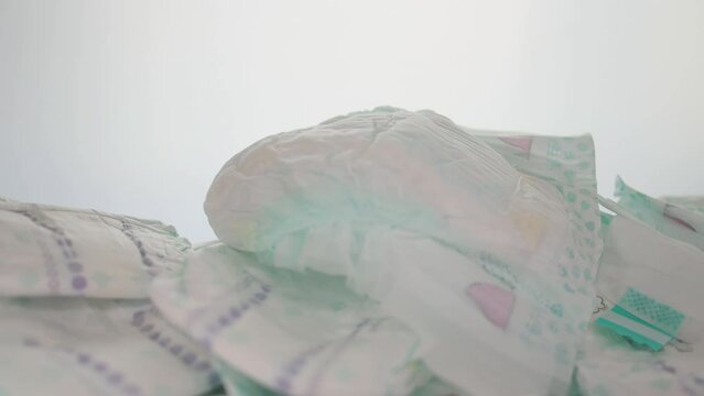 a lot of scattered baby diapers on a white background. The concept of natural cotton diapers, hypoallergenic and comfortable. Leakage protection. Copy space for text. Slow motion