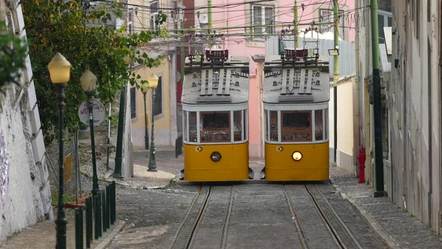 Lisbon, Portugal - 4 October 2023: 4K video with the landmark trams from Lisbon. Beautiful view with vintage yellow trams on the hills of Lisbon.