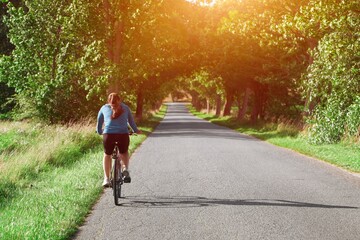 back view of a young woman riding a bicycle in the countryside. traveling by bike. outdoor activity.