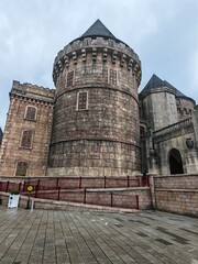 . It appears to be a castle with medieval architecture. The building has turrets and towers, and it is surrounded by a cloudy sky. It is a historic site and a fortress.
