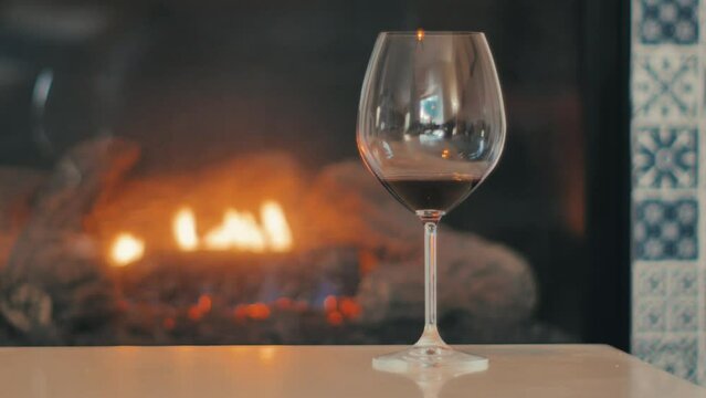 Red wine in tall stemmed glass in front of fireplace inside 
