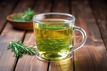 green herbal tea in a transparent cup on a wooden table