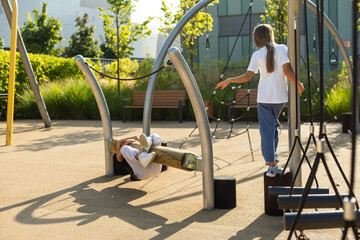 Fototapeta premium Teenager girl doing exercises on the school playground on a summer, sunny day.