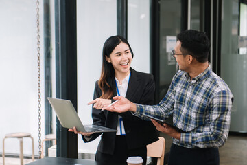 Happy businesspeople while collaborating on a new project in an office. diverse businesspeople using a laptop and tablet