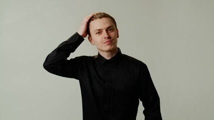 A winsome guy model poses for a photo shoot, creation a professional portfolio or mens magazine. A young confident smiling actor playfully and coquettishly straightens hair for filming a shampoo