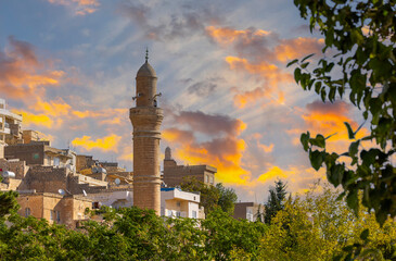 Mardin cityscape with roof of a Turkish hammam and minarets in Mardin old town at sunset,...