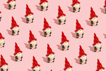 Beautiful ceramic Christmas gnome with red hat  on pink background. Winter holiday concept. Pink Christmas pattern.