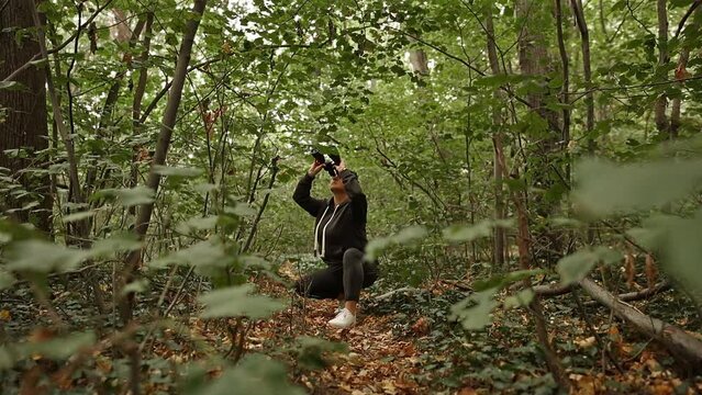 Woman using binoculars for birdwatching and observing other animals in nature.