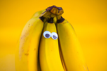 Bananas on a string, yellow background, funny bananas with eyes